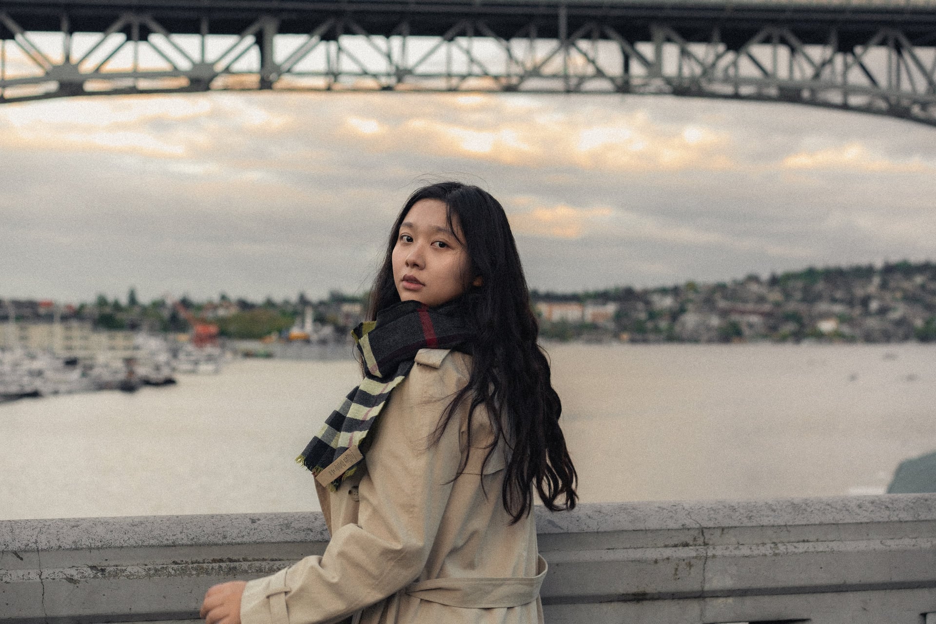 A portrait beneath a bridge overlooking the water at dusk