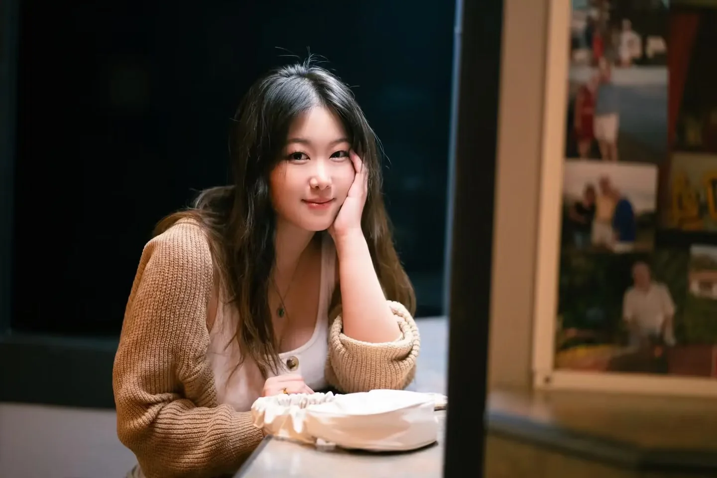 A smiling woman seated at a café table in warm light