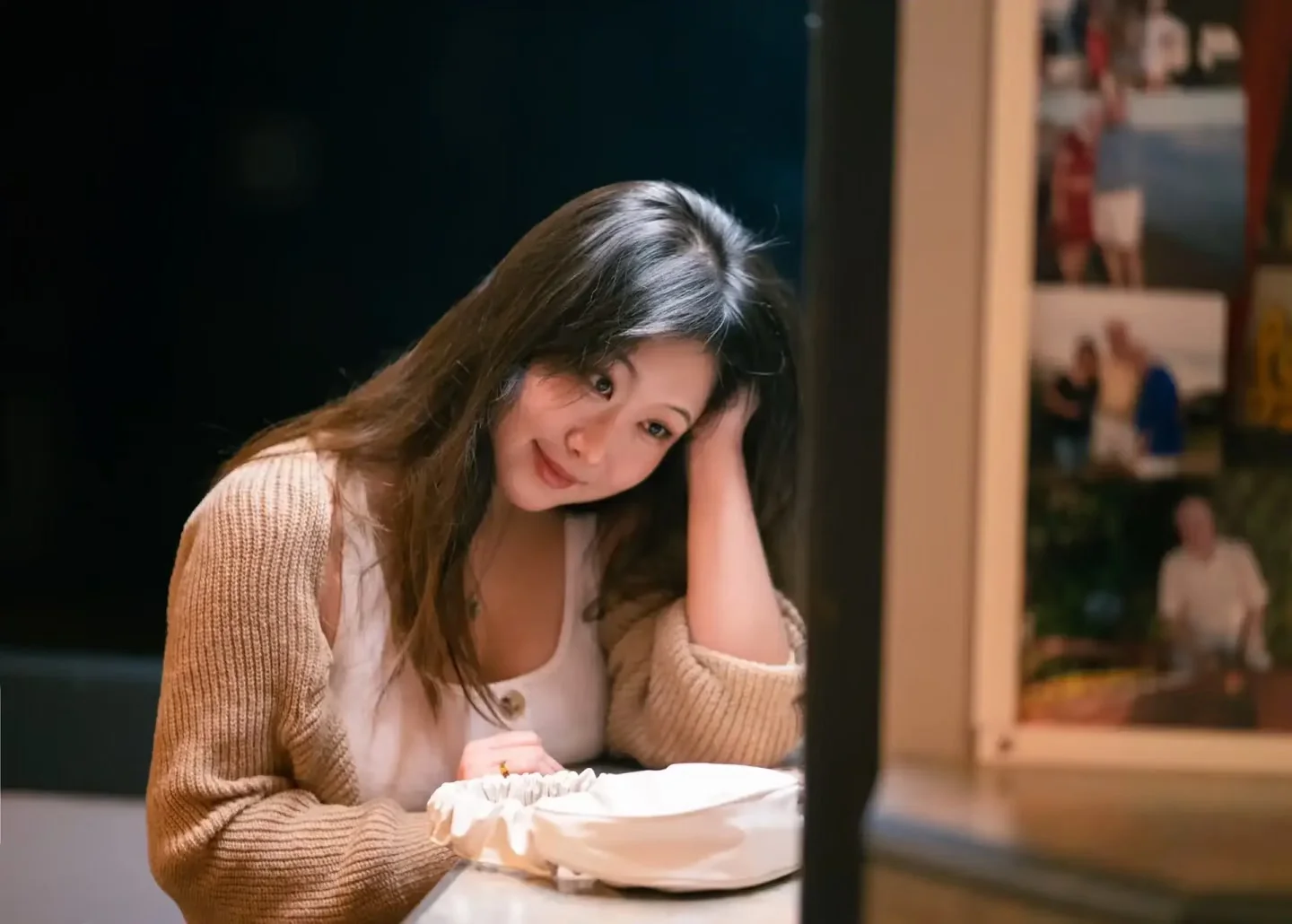 A woman looking down at her dessert beside a café window