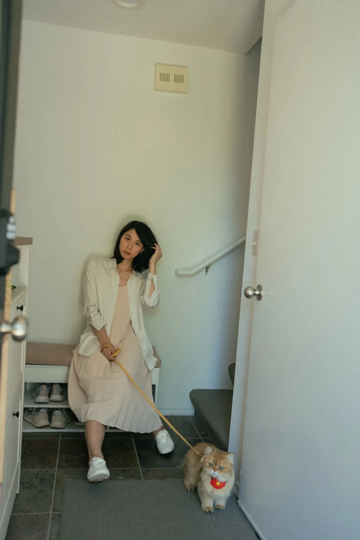 A woman seated by an open doorway with her cat on the floor