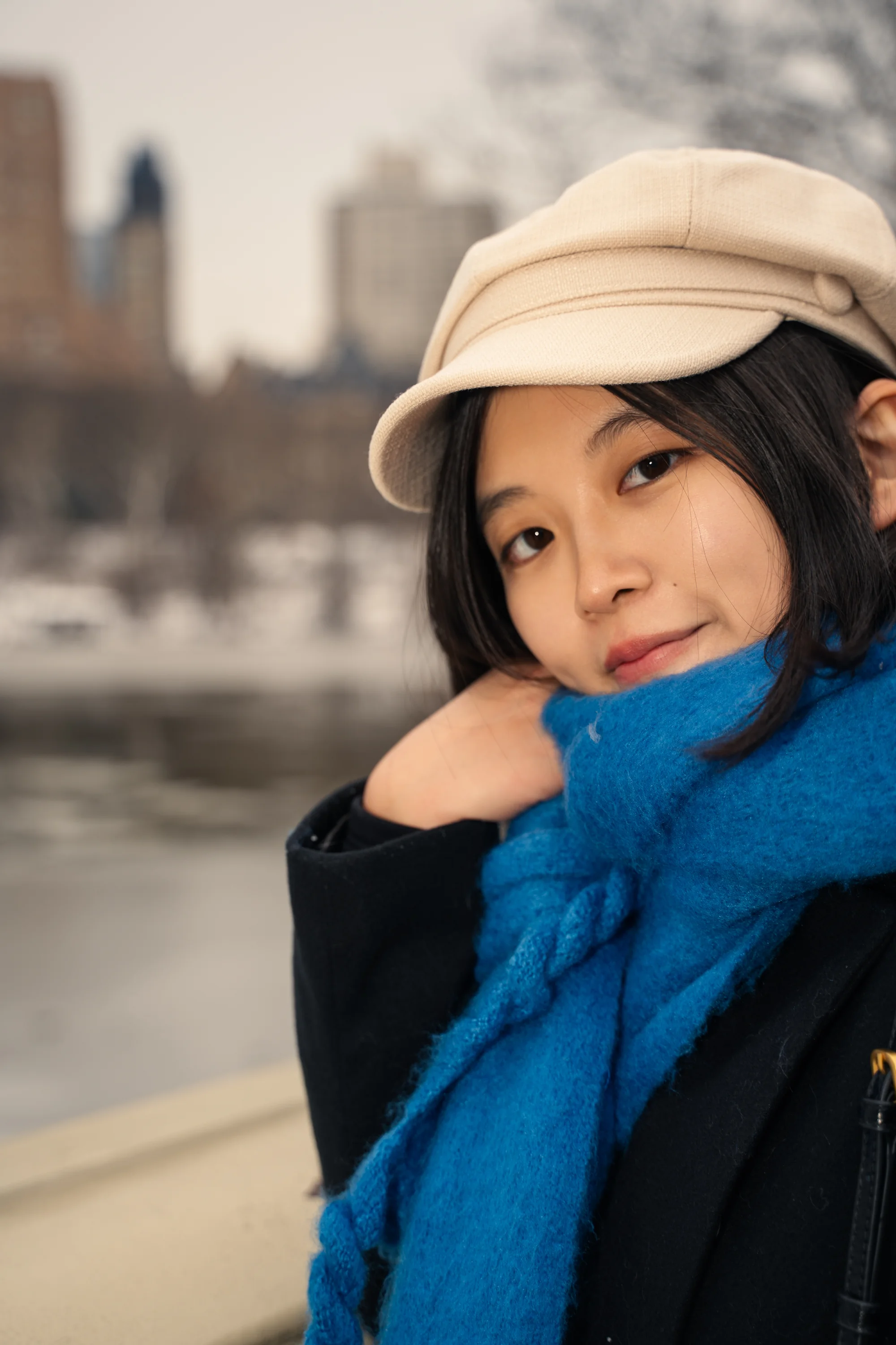 A close portrait of a woman in a cream cap and blue scarf