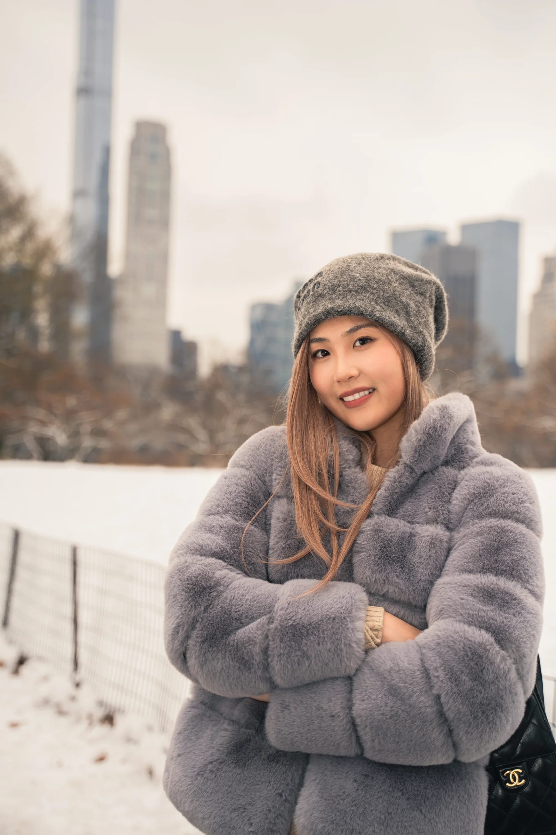 A smiling woman in a winter coat with city towers in the distance
