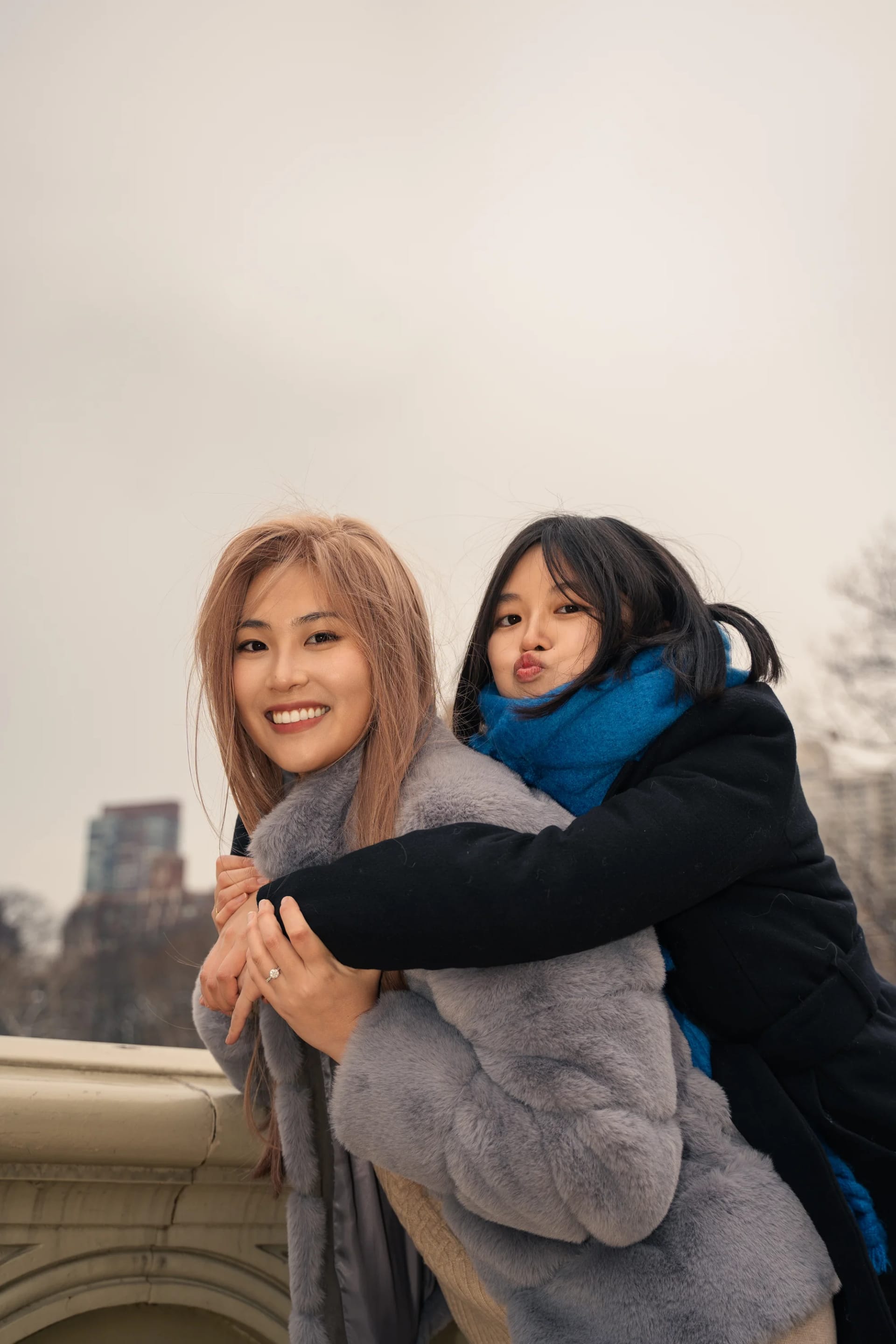 Two friends embracing beside a stone bridge railing
