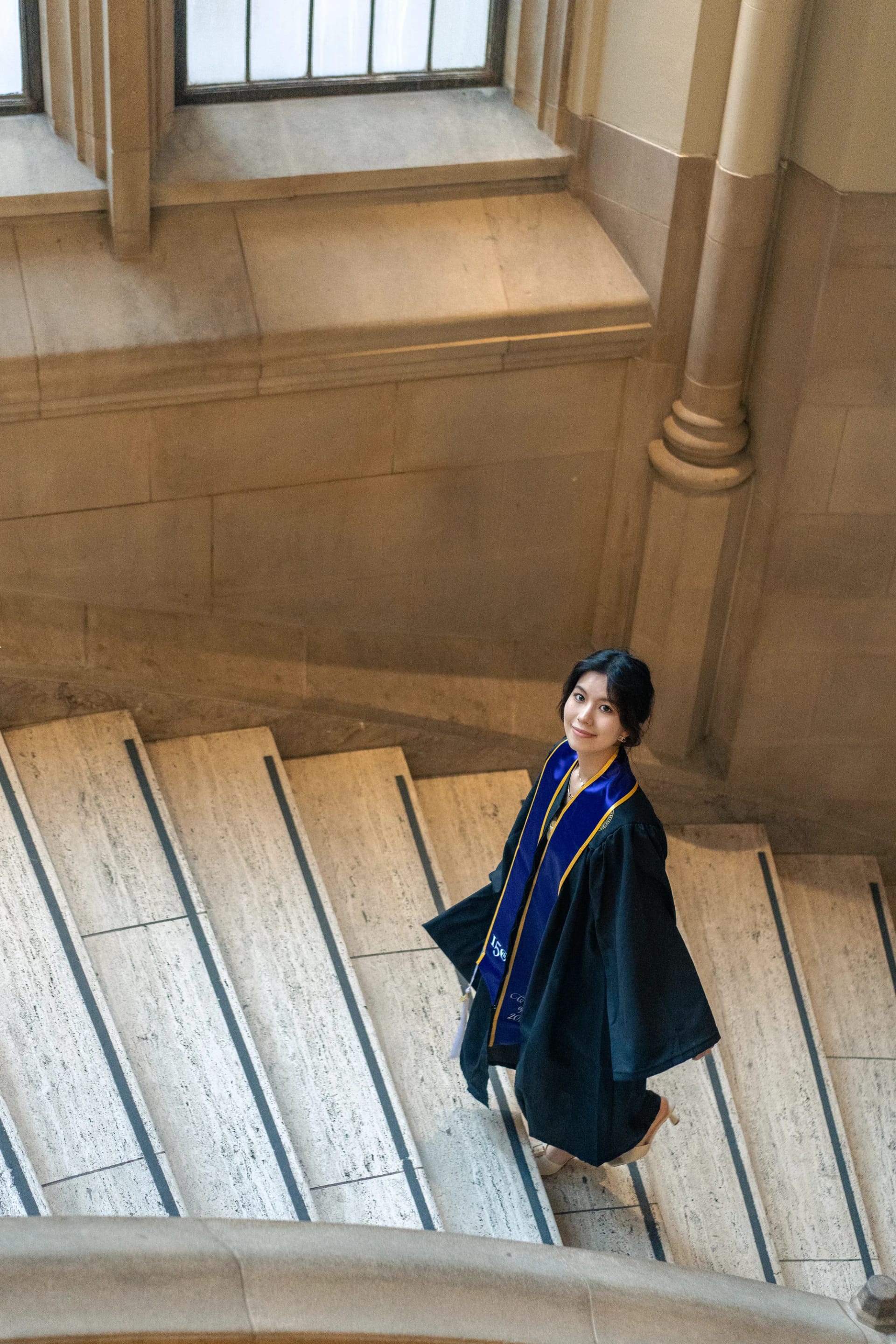 An overhead view of a graduate on a winding stone staircase