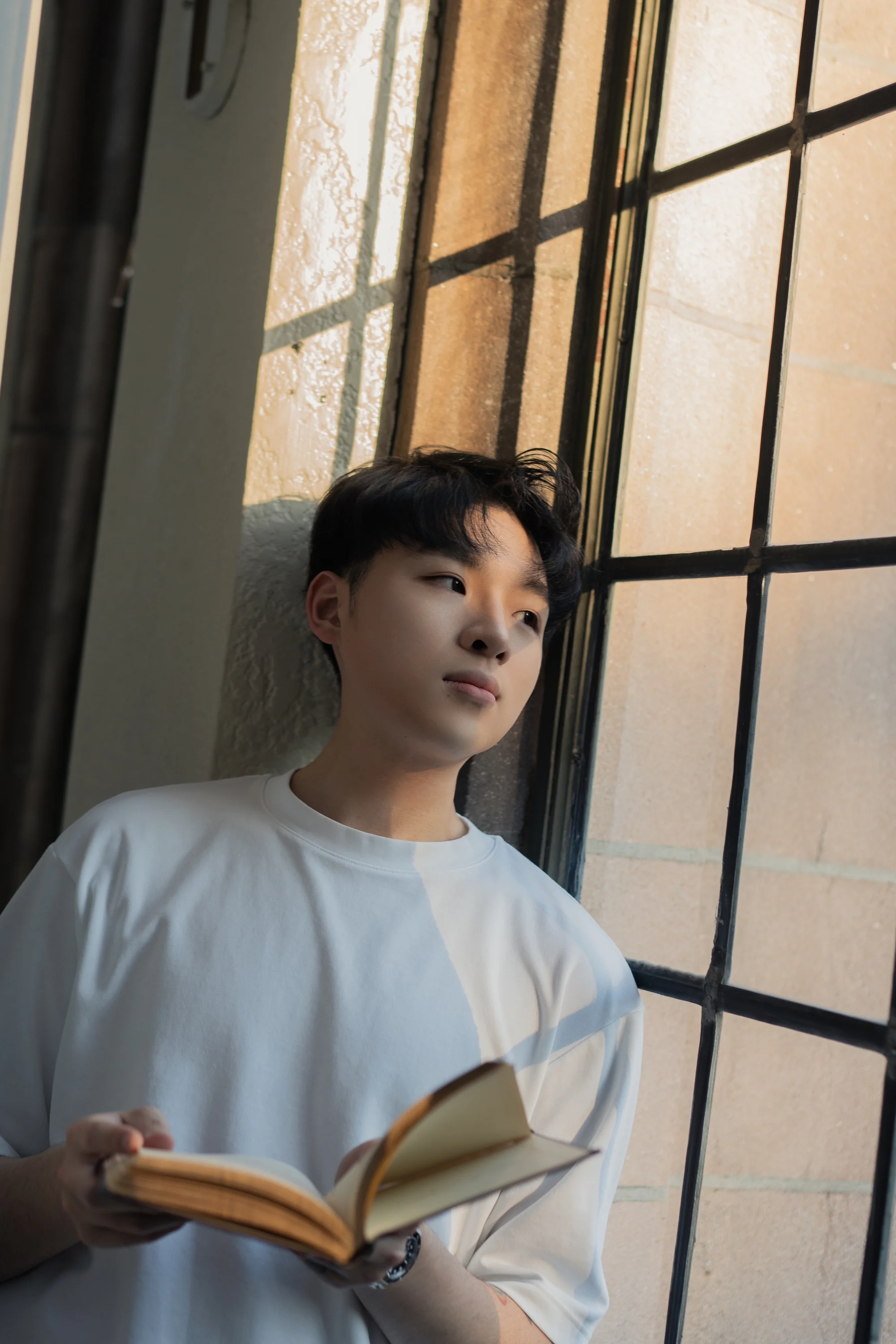 A graduate reading in warm light beside a leaded window