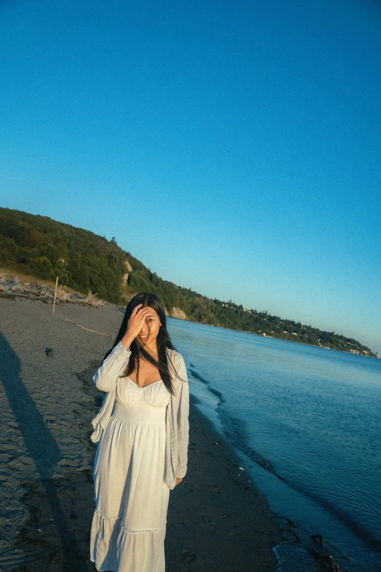 A woman brushing her hair away from her face on the beach