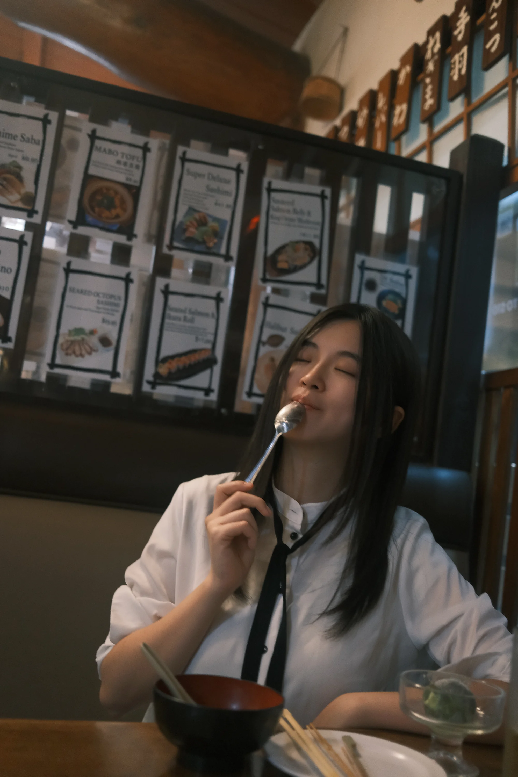 A diner enjoying a skewer beneath framed restaurant menus