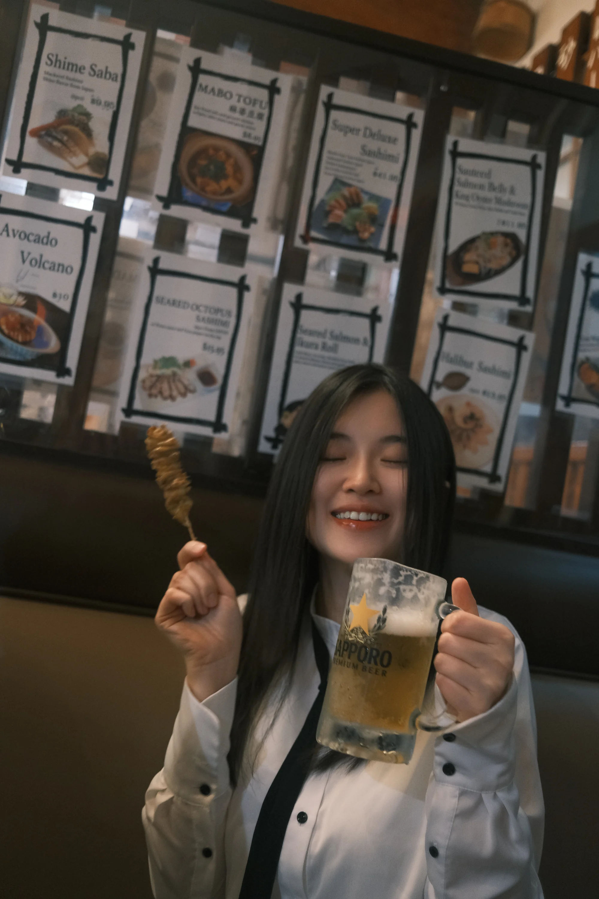 A smiling diner holding a skewer and a glass at dinner