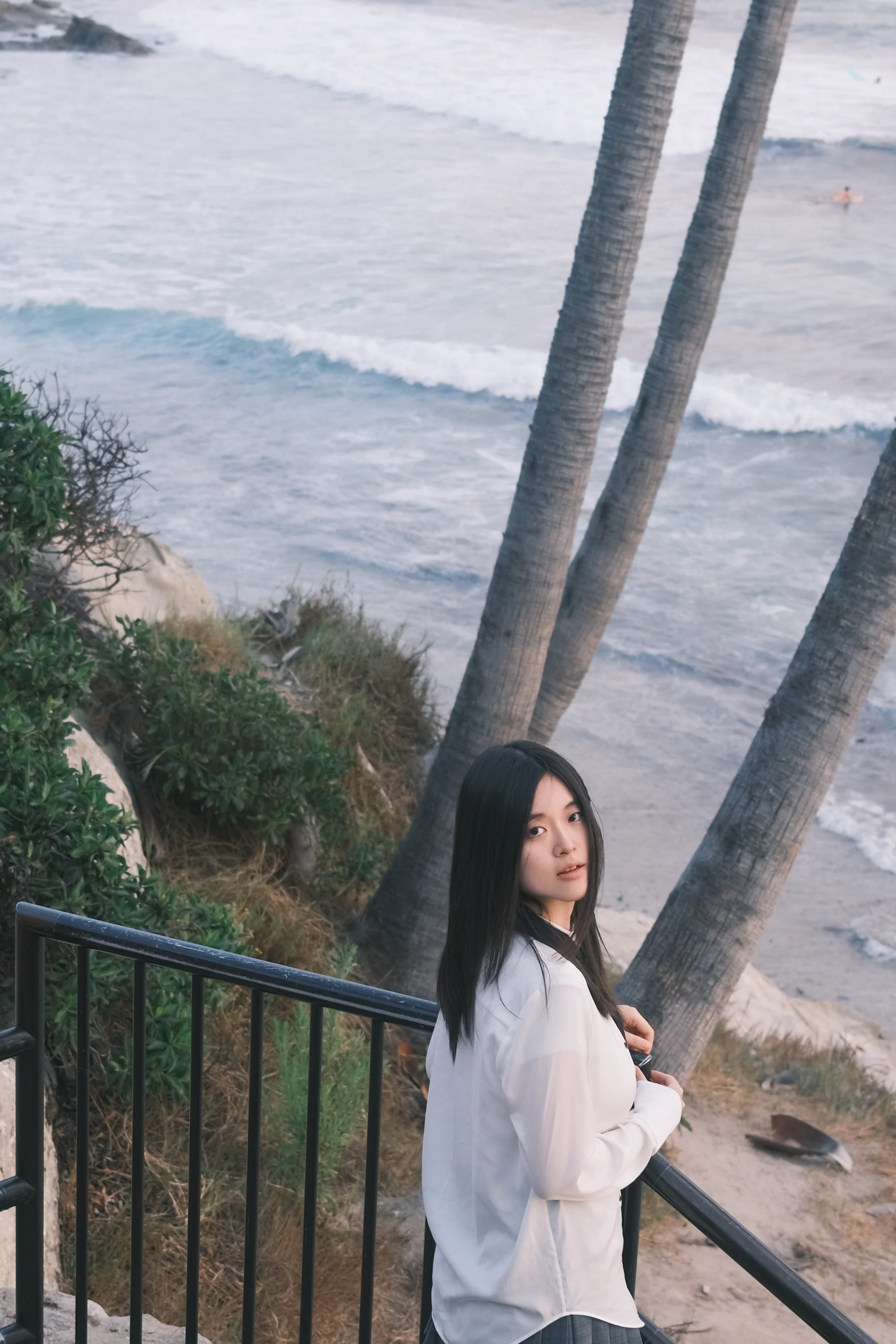 A portrait framed by palm trees and waves along the coast