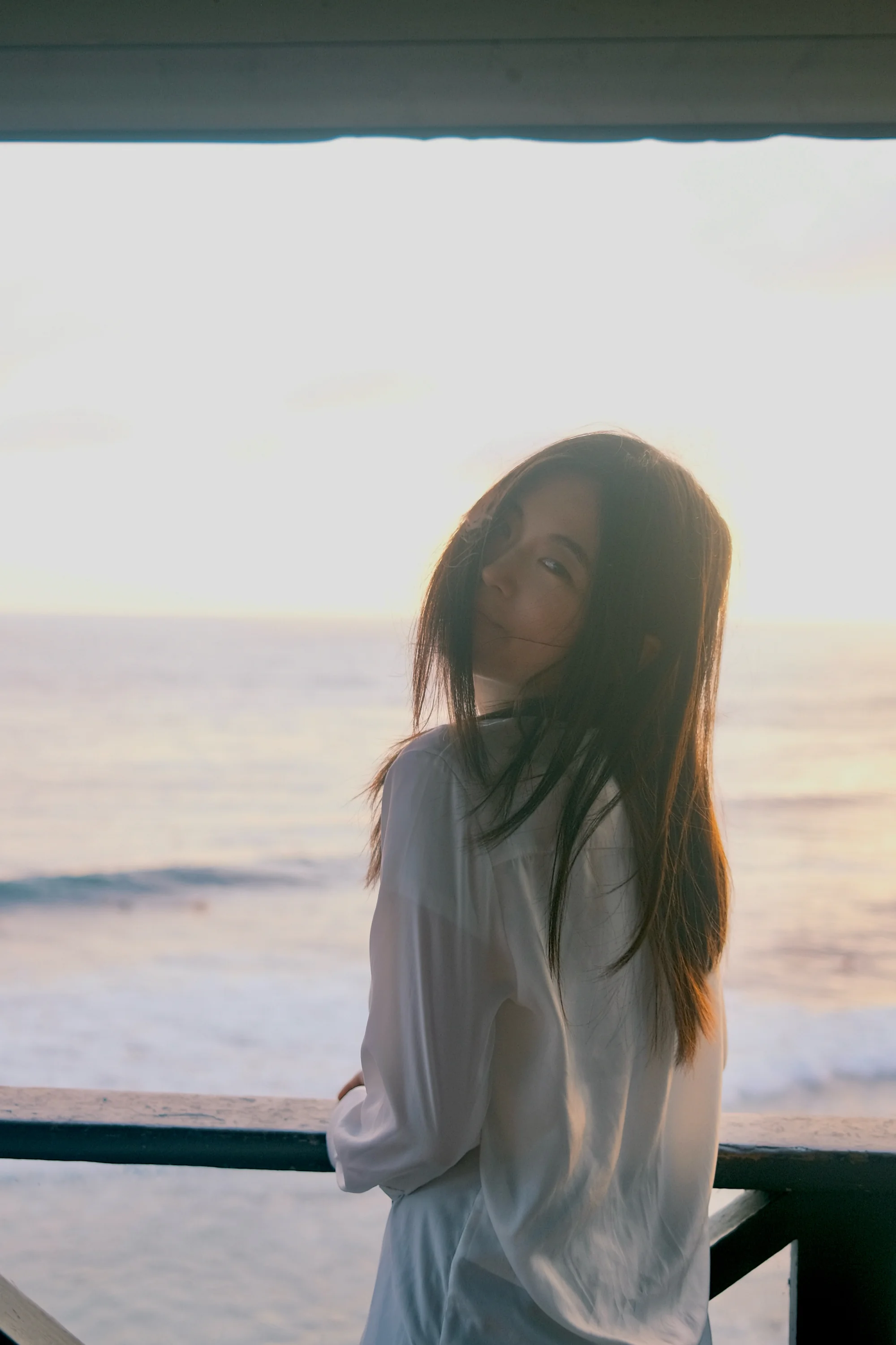A softly backlit portrait with the ocean beyond a window