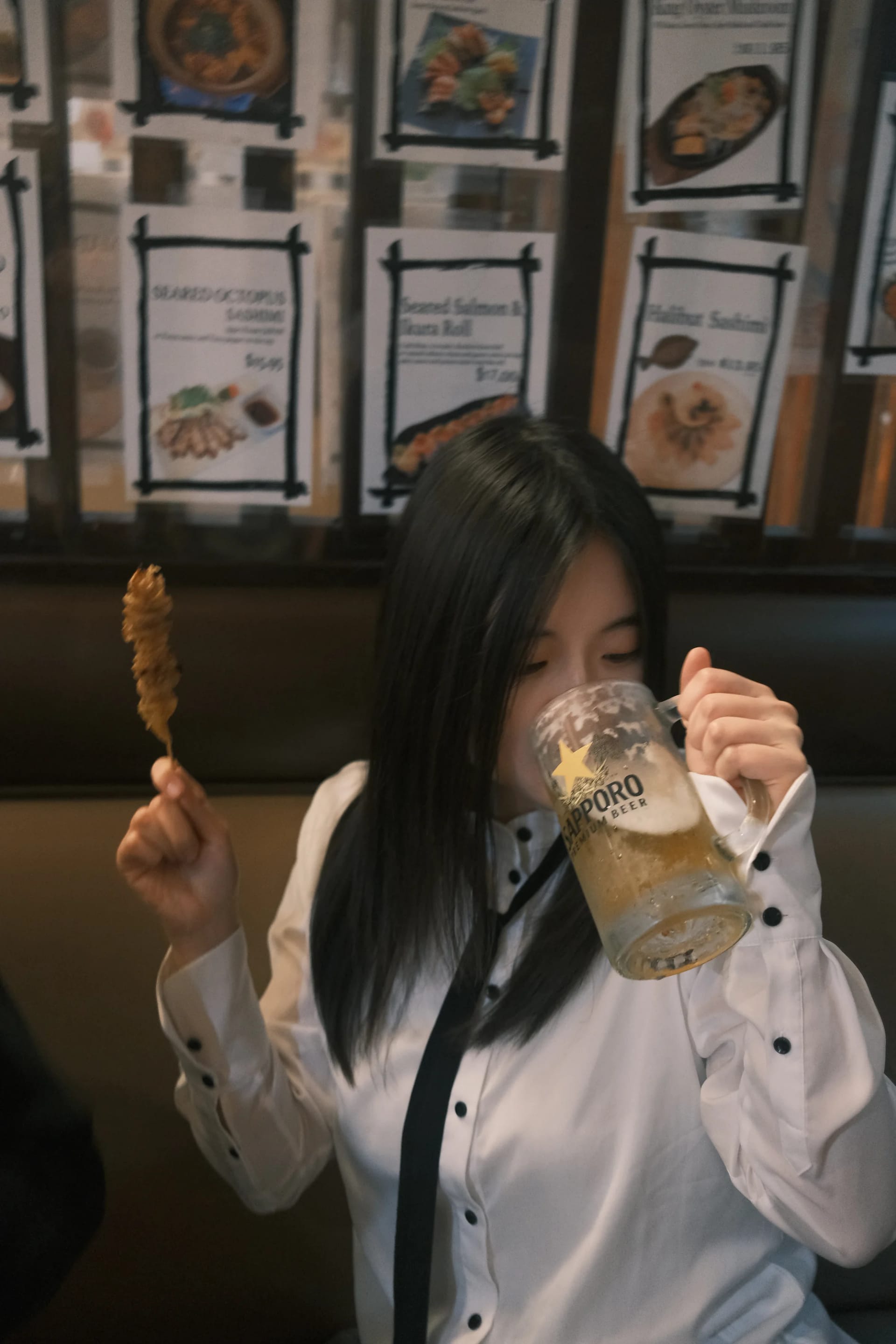 A diner smiling while holding a skewer and a glass