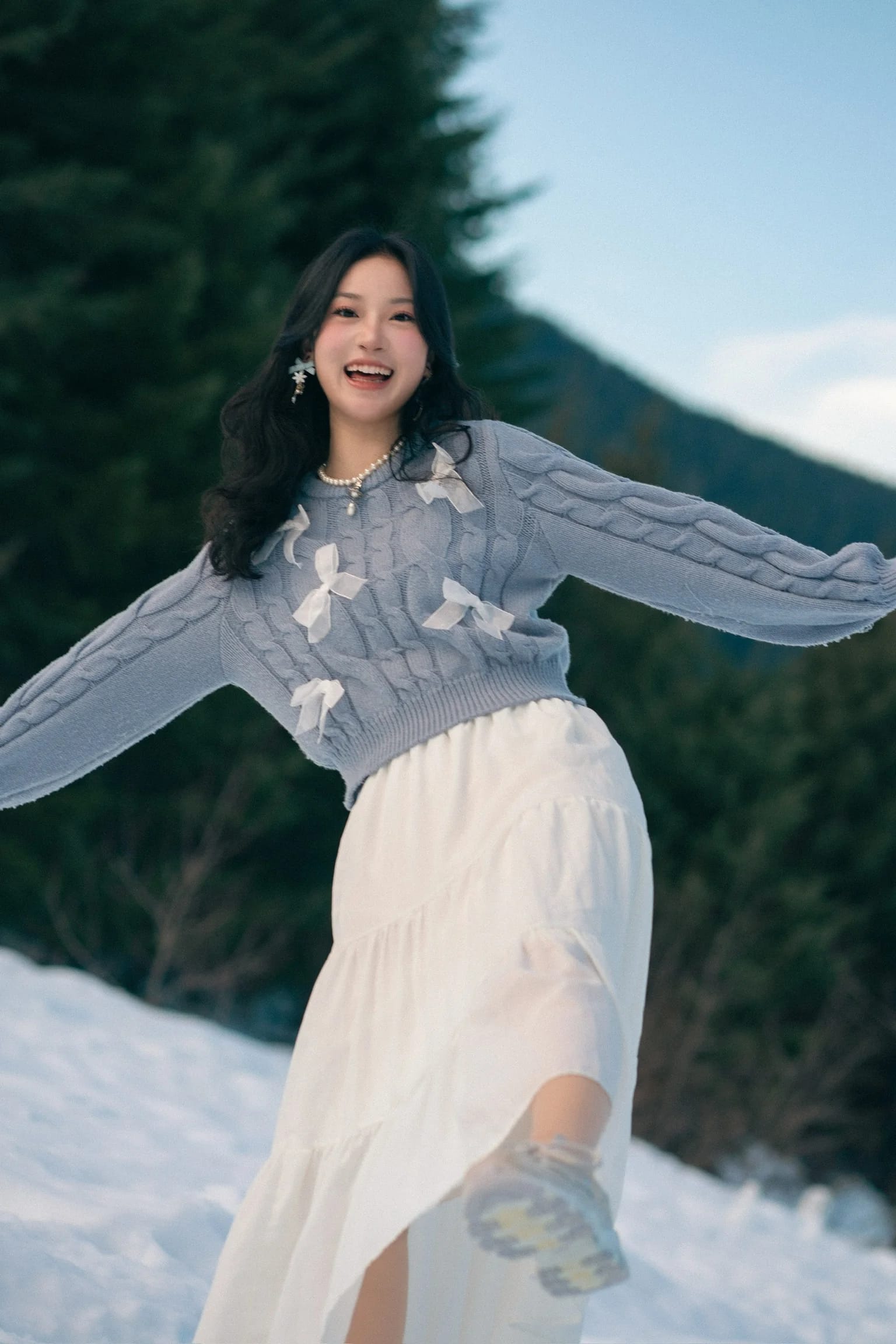 A woman spreading her arms in a snowy mountain clearing