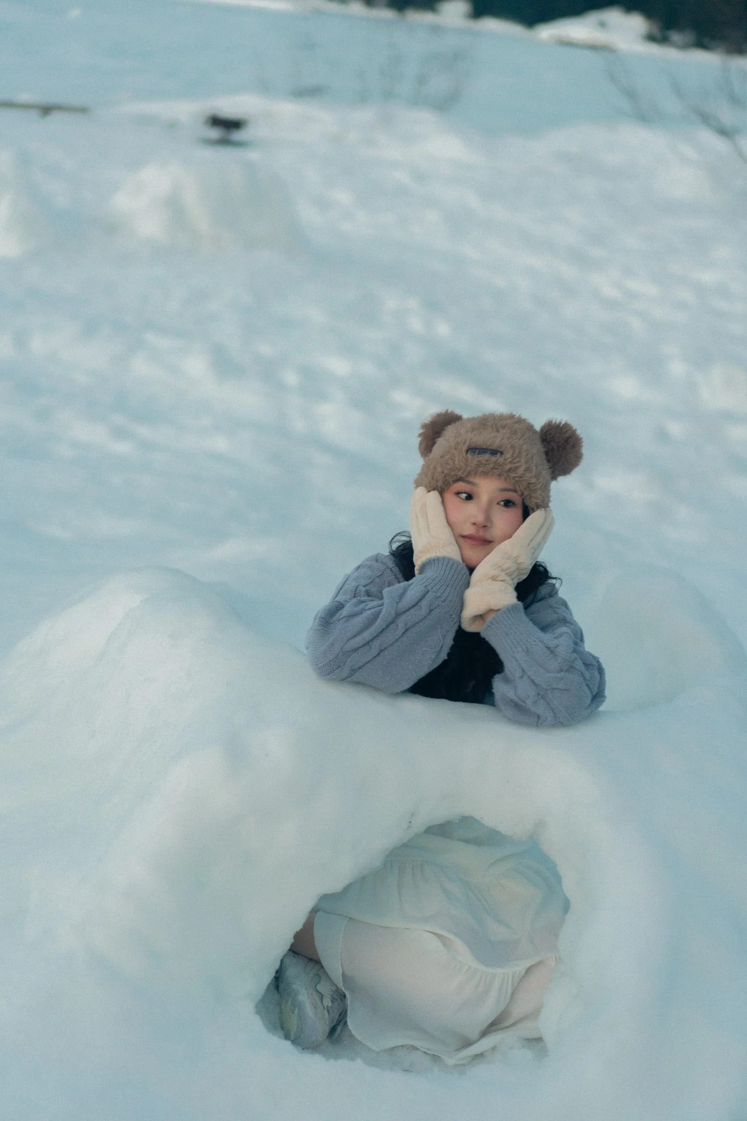 An overhead portrait of a woman nestled in a snowy hollow