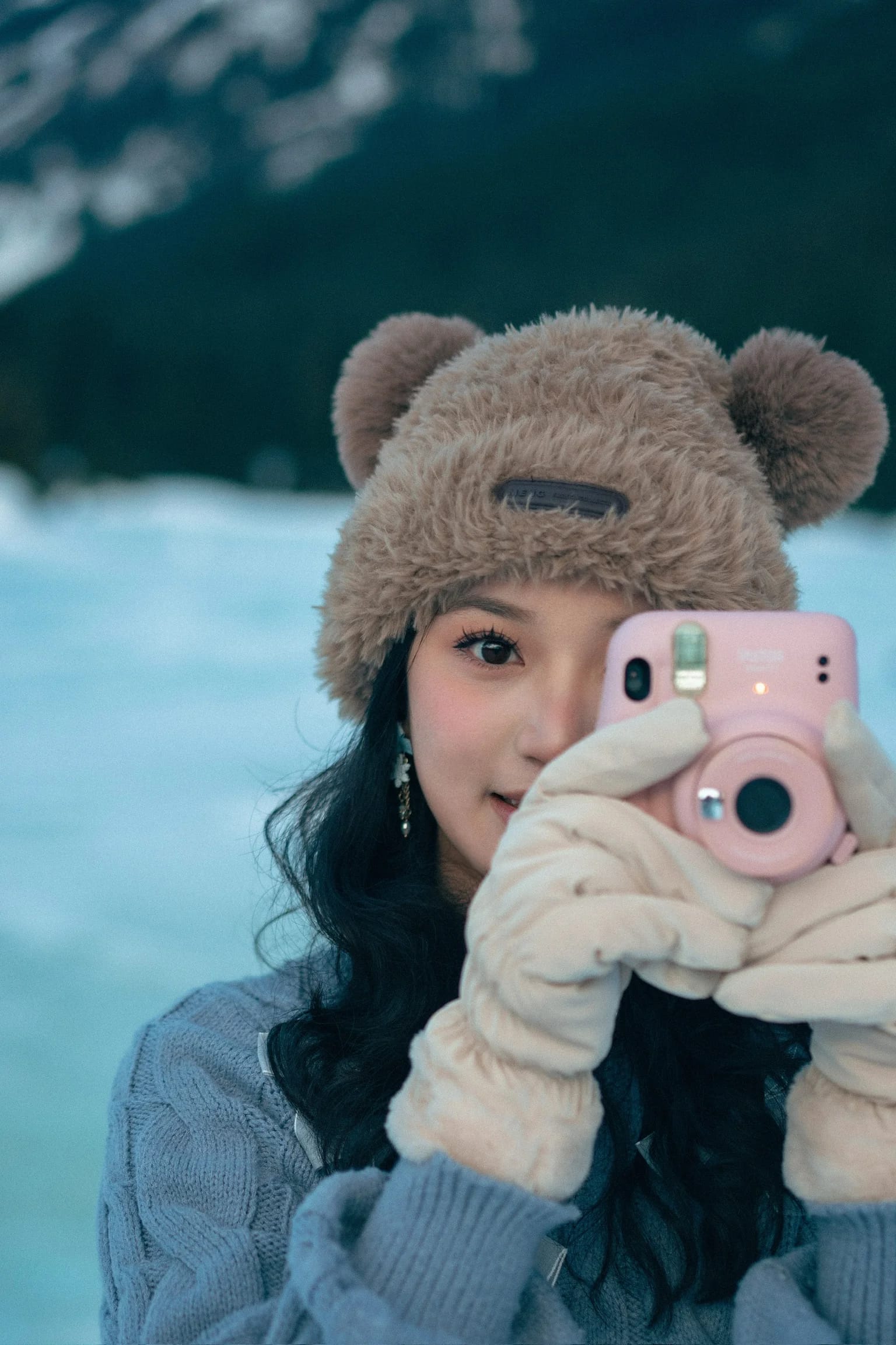 A woman holding a pink instant camera up to her face