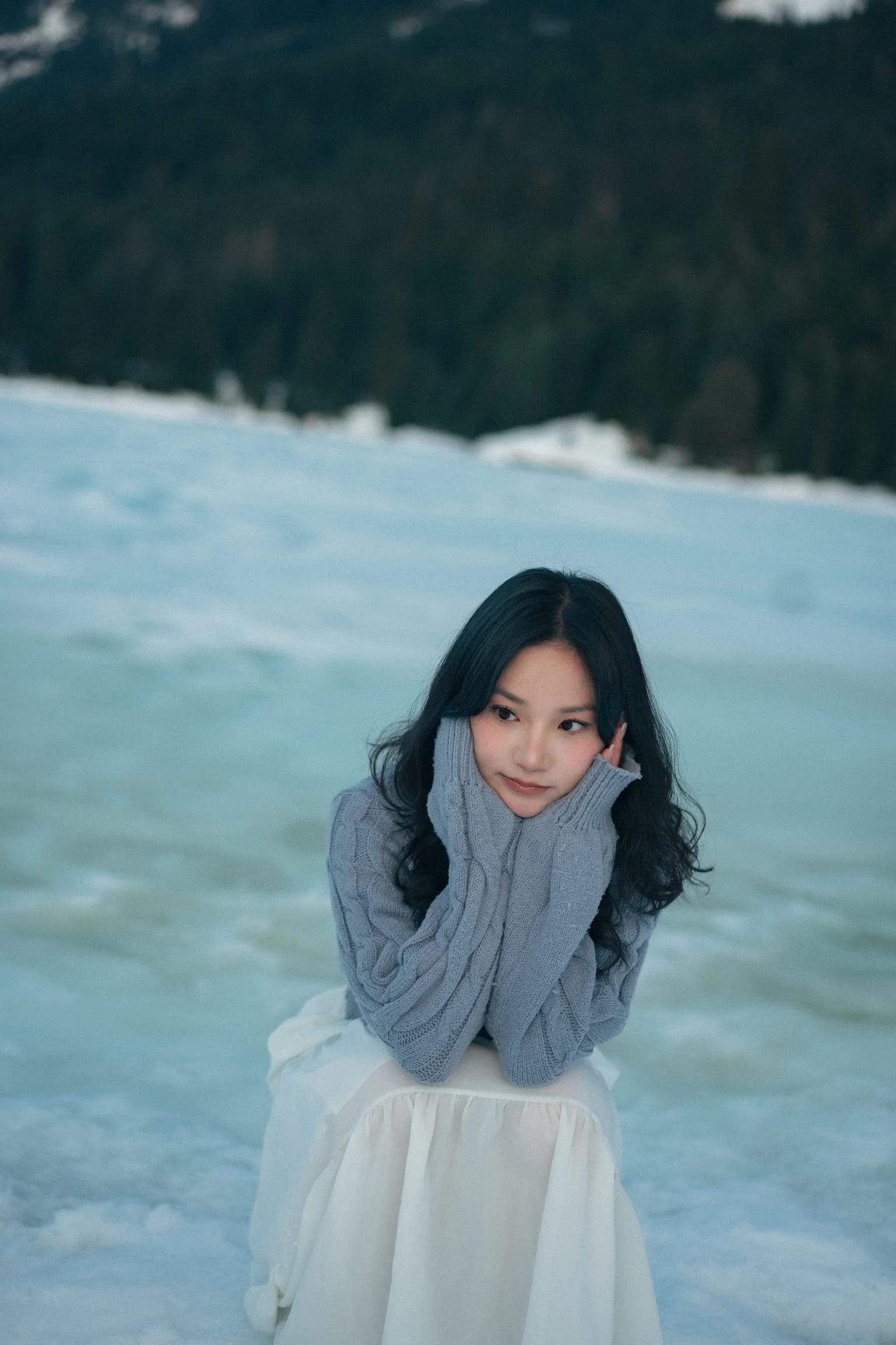 A woman resting her chin in her hands above the snow