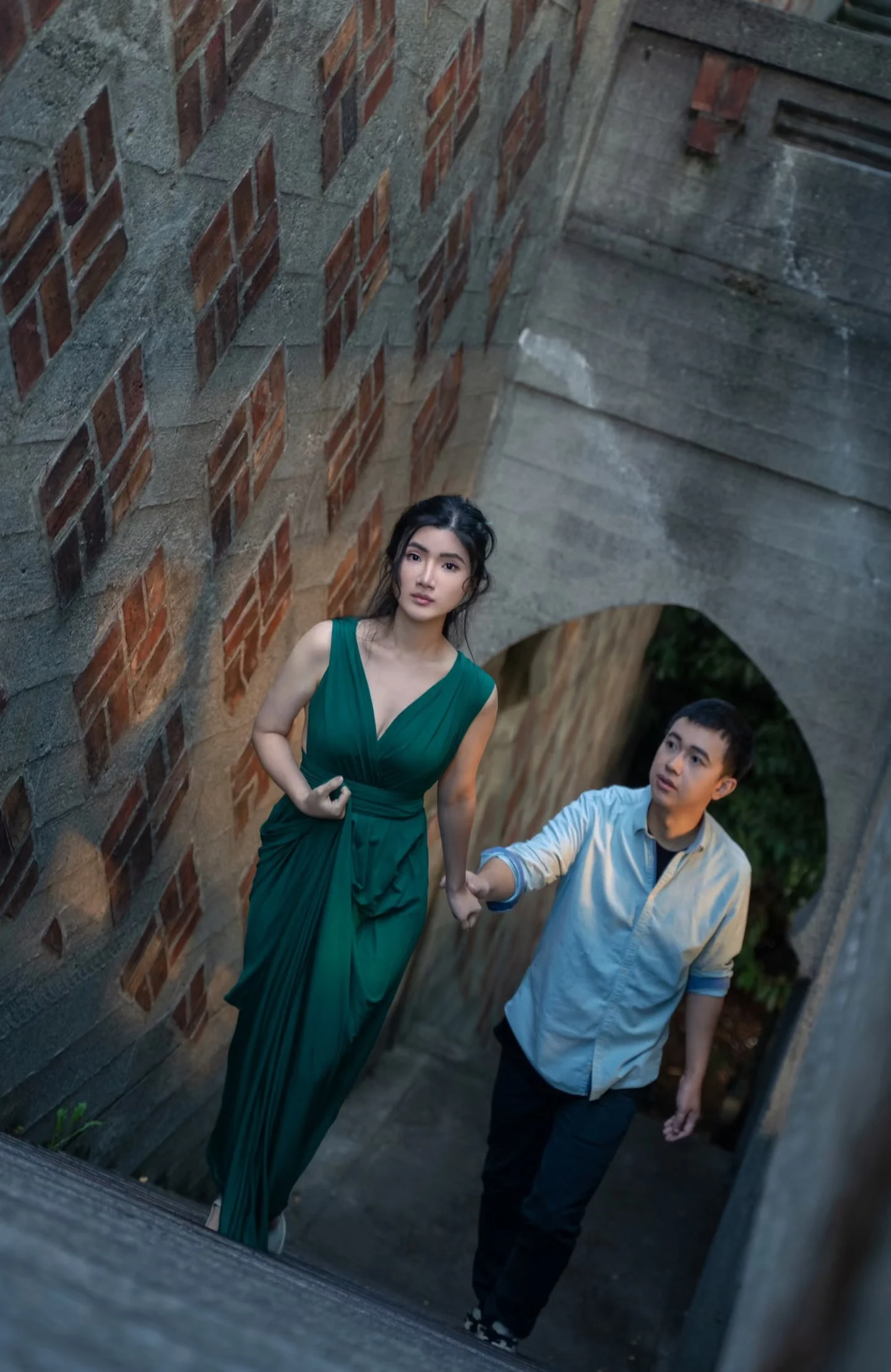 A couple on a narrow staircase beside a brick building