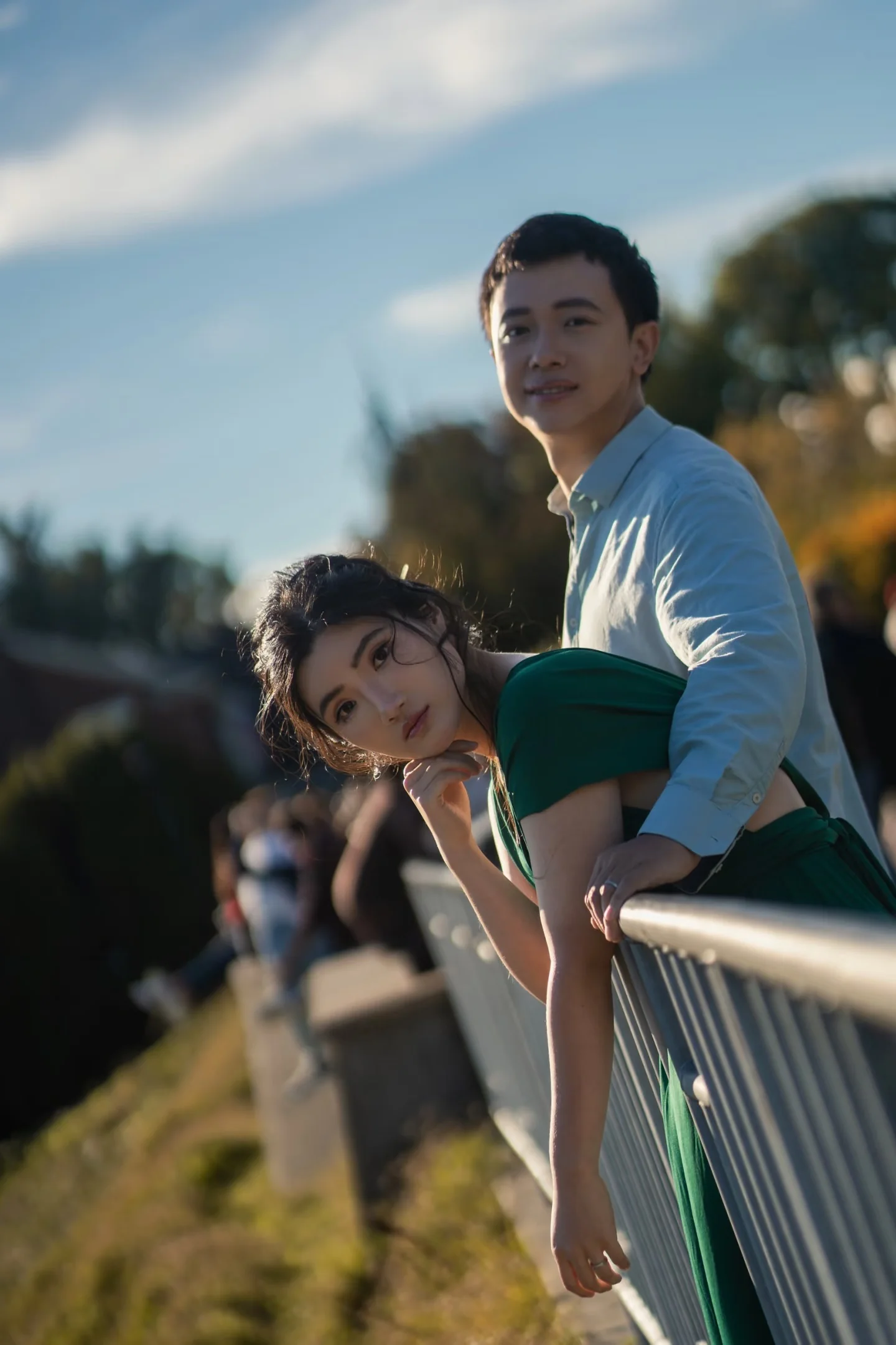 A couple leaning against a railing in evening light