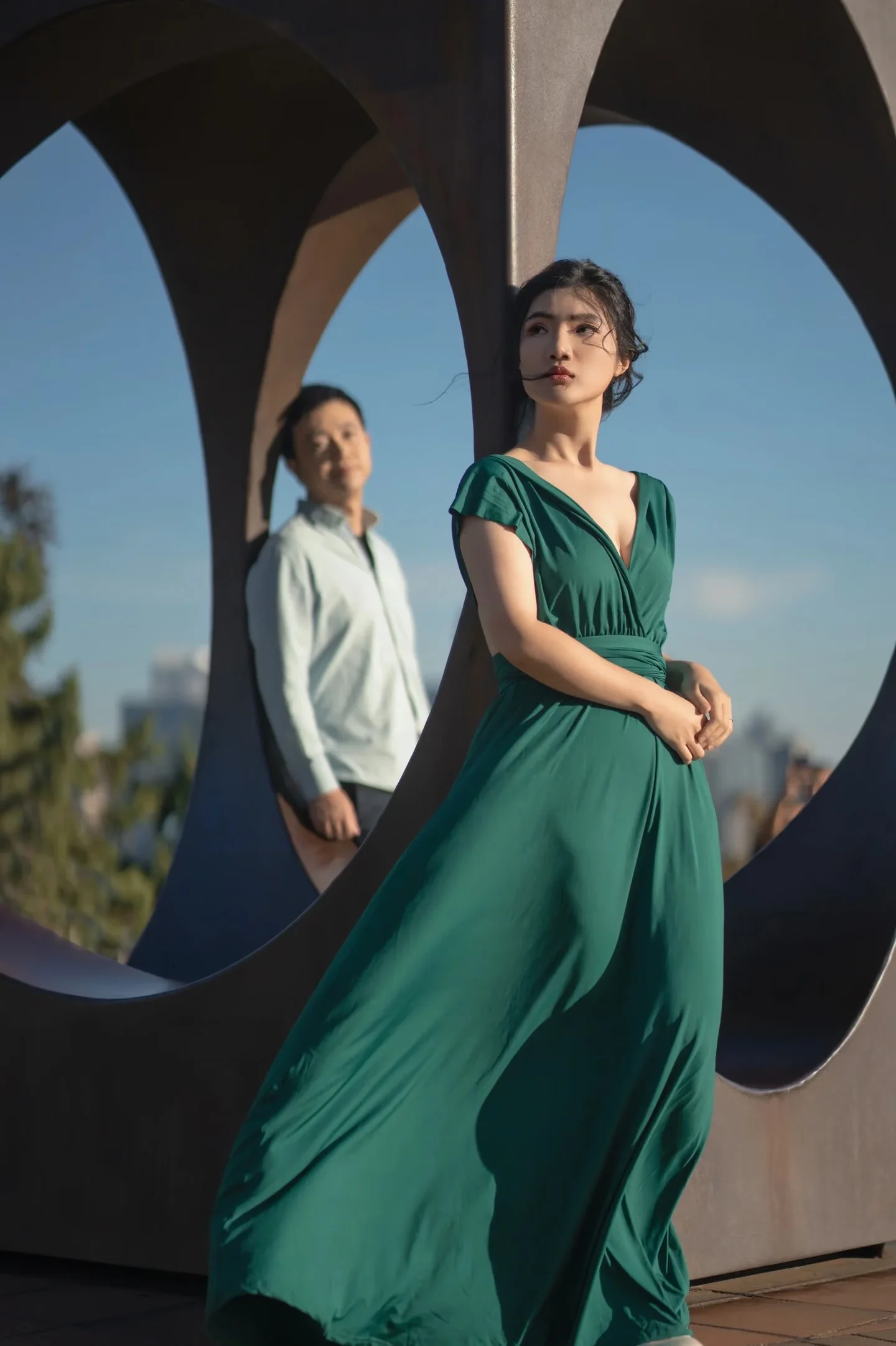 A couple framed by the curved openings of a large metal sculpture
