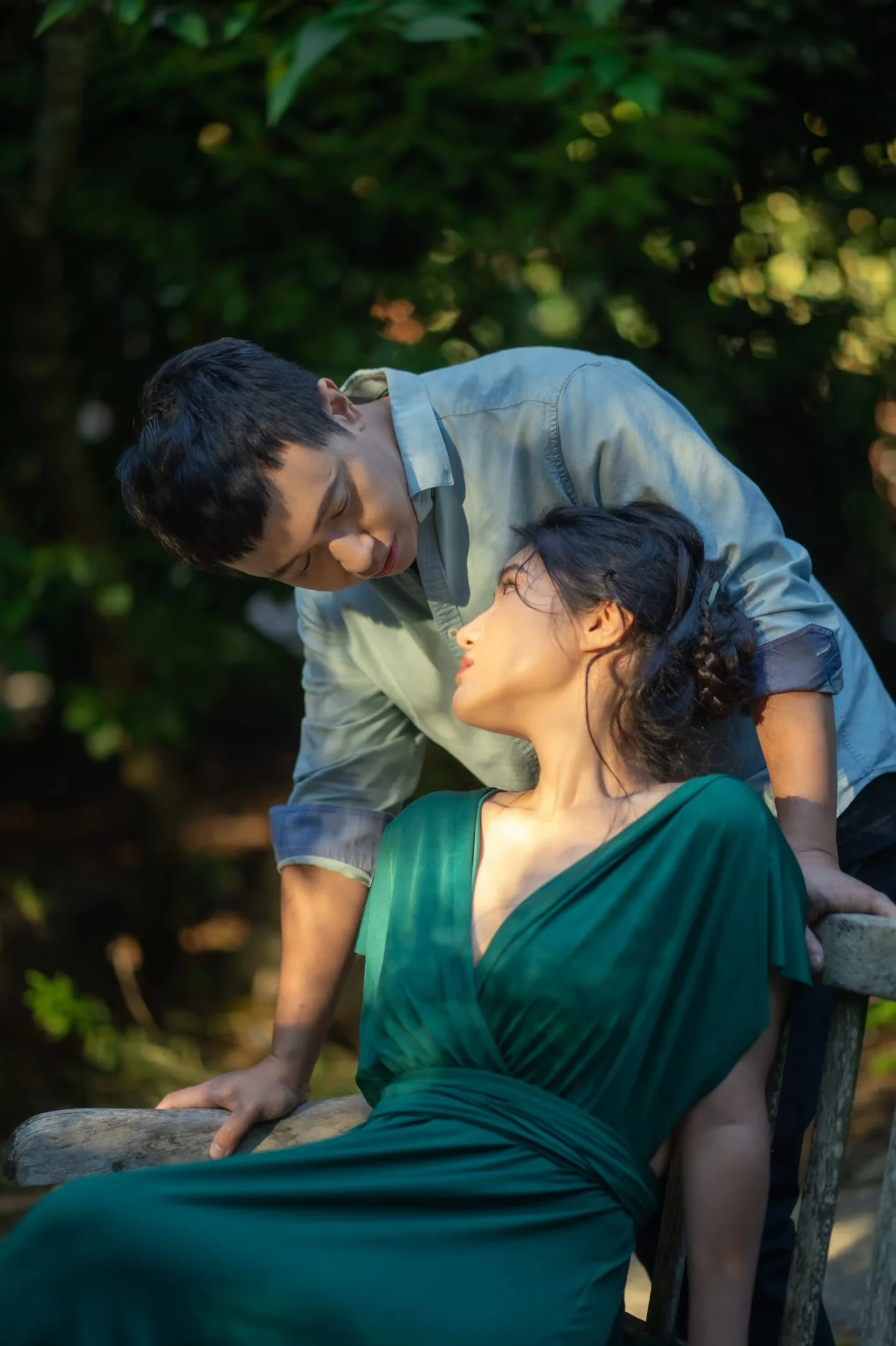 A man leaning toward a woman seated in a green dress