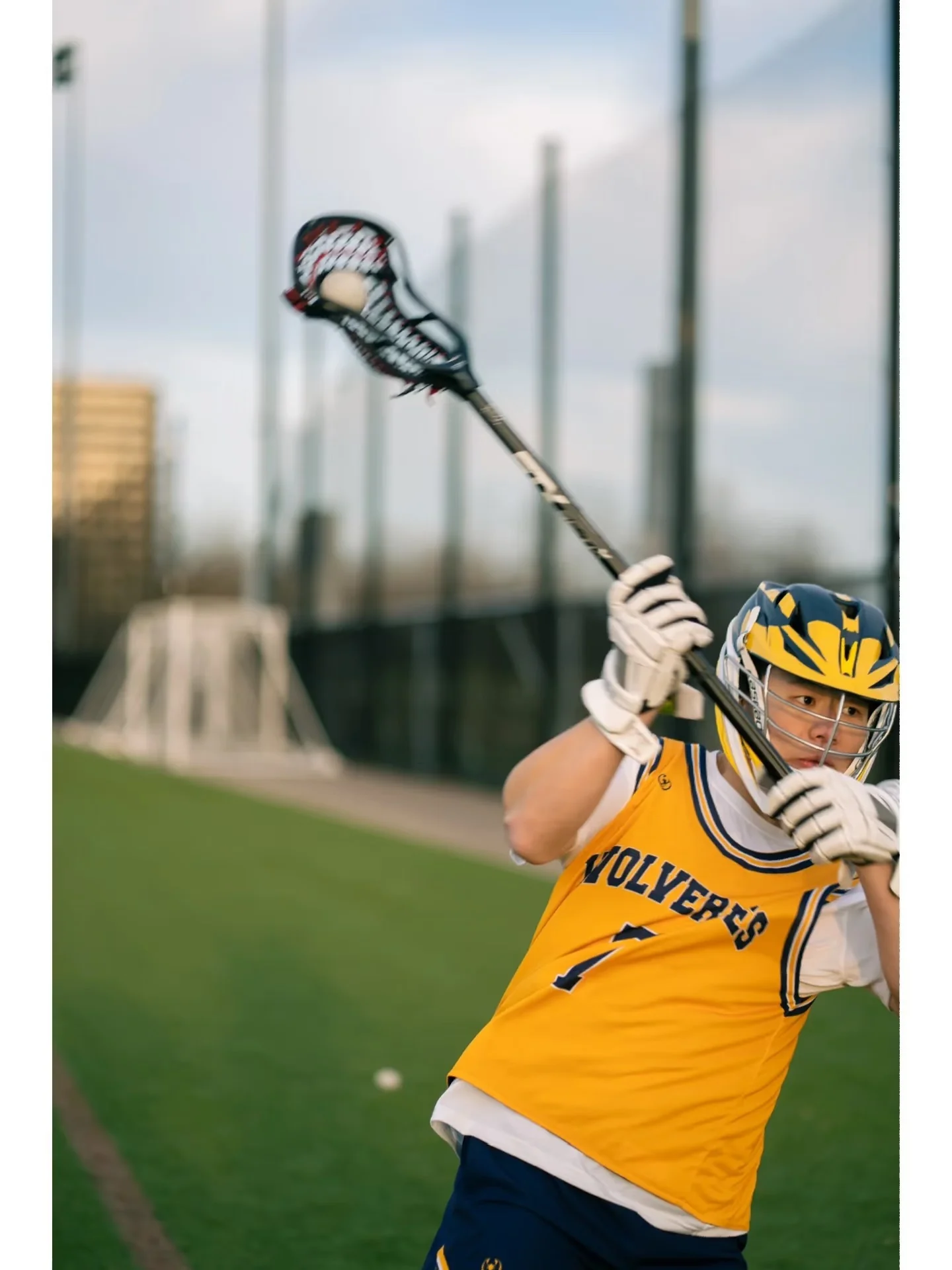 A lacrosse player winding up for a shot beside the goal