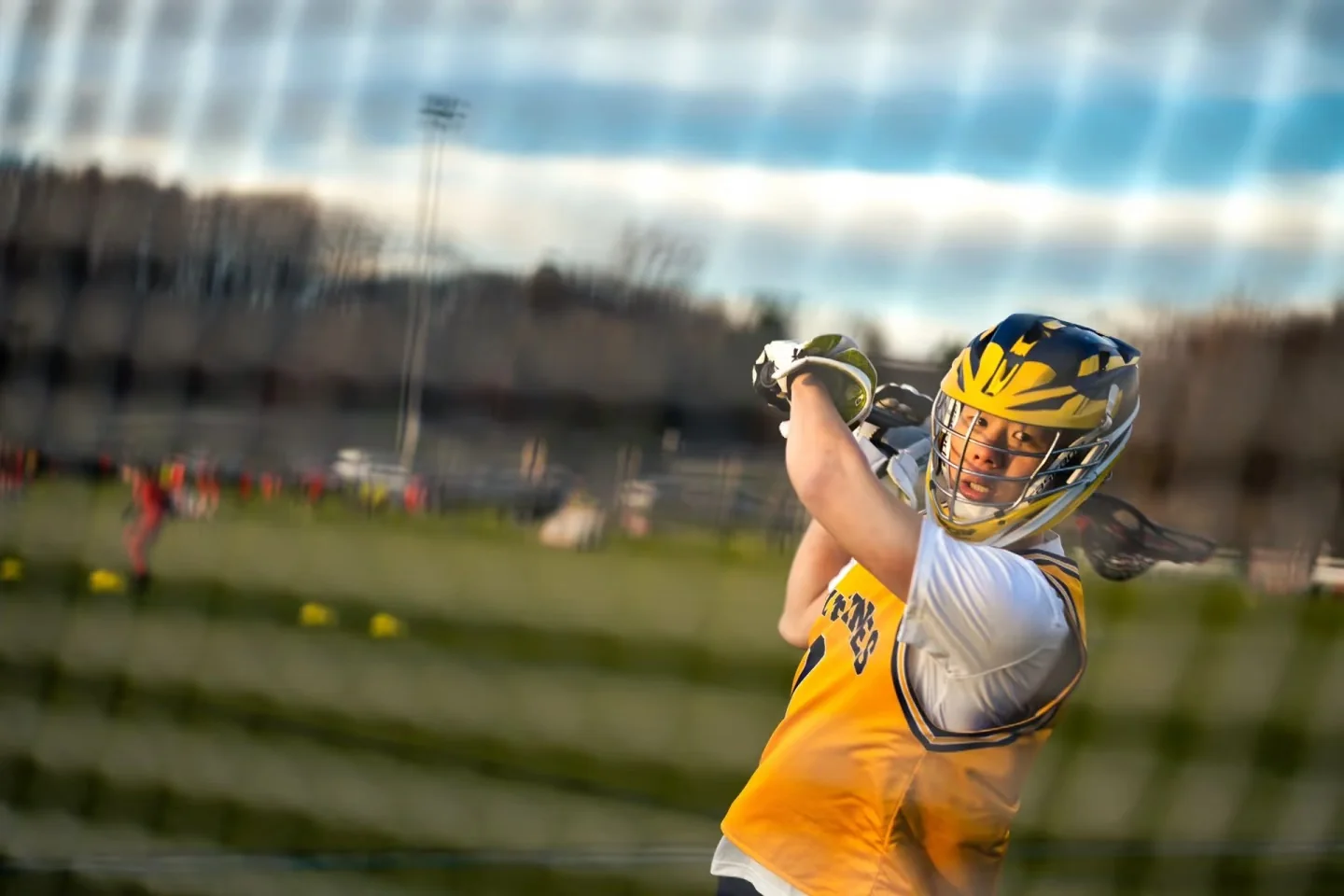 A lacrosse player swinging his stick across the field