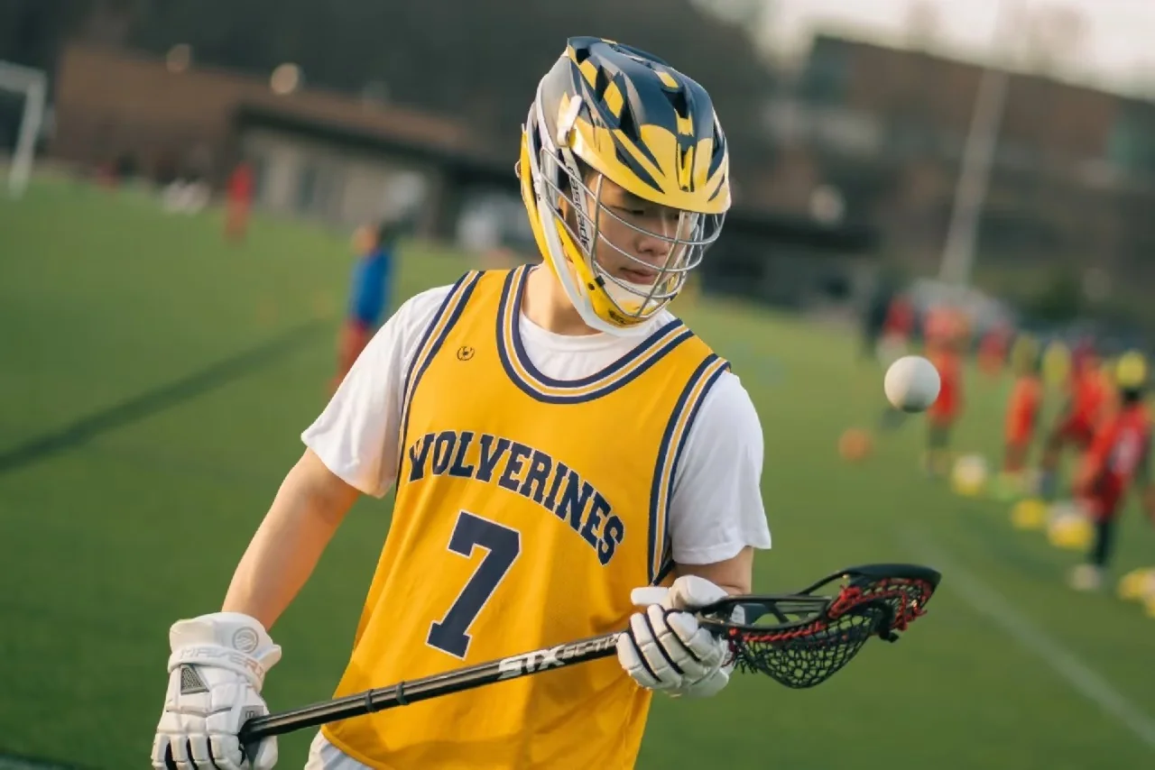 A lacrosse player holding his stick diagonally across his jersey