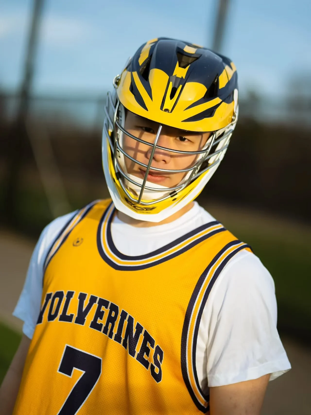 A lacrosse player wearing a yellow helmet and jersey on the field