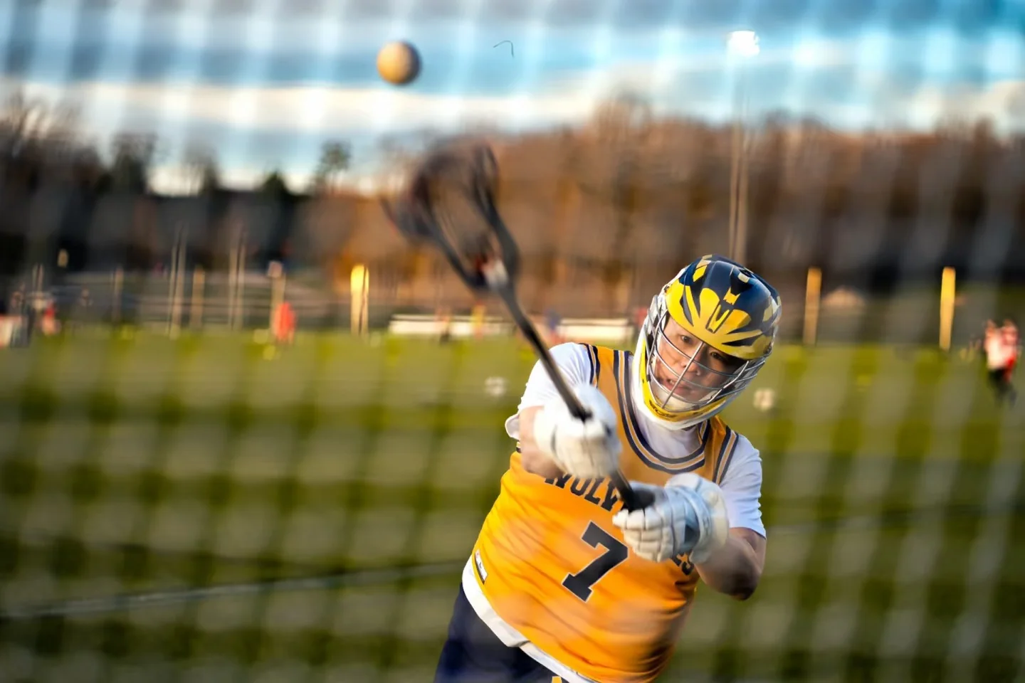 A lacrosse ball in flight as a player follows through on a shot