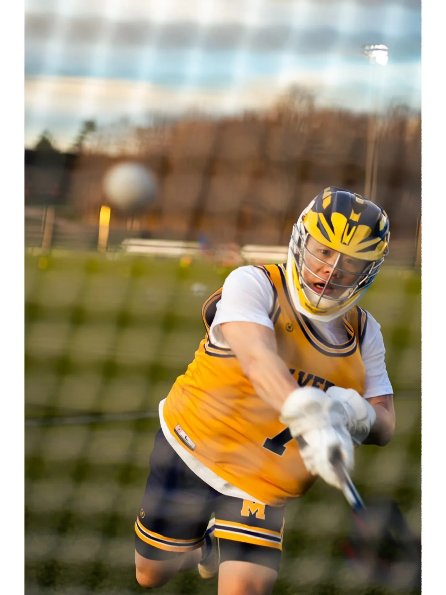A lacrosse player following through on a shot behind the goal net