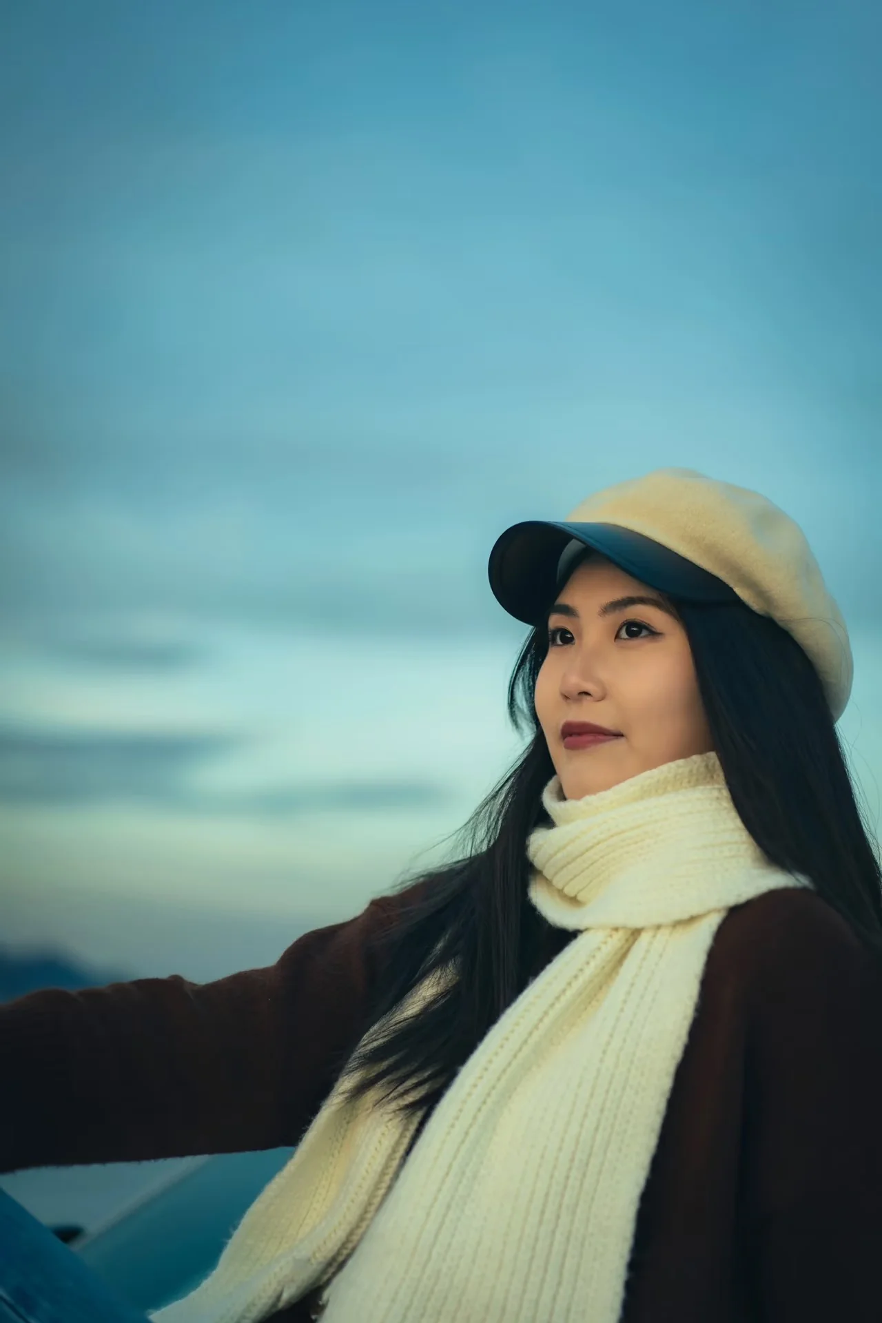 A woman in a cream cap and white scarf beside the car