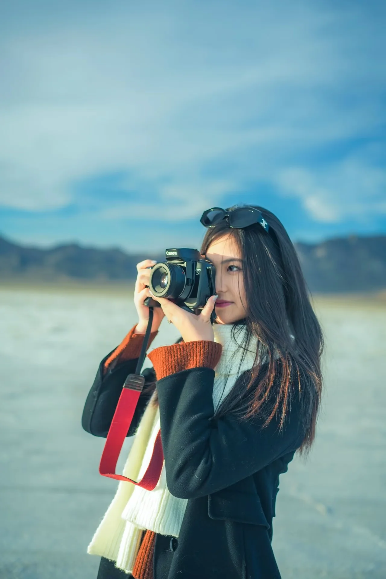 A woman holding a camera on open salt flats