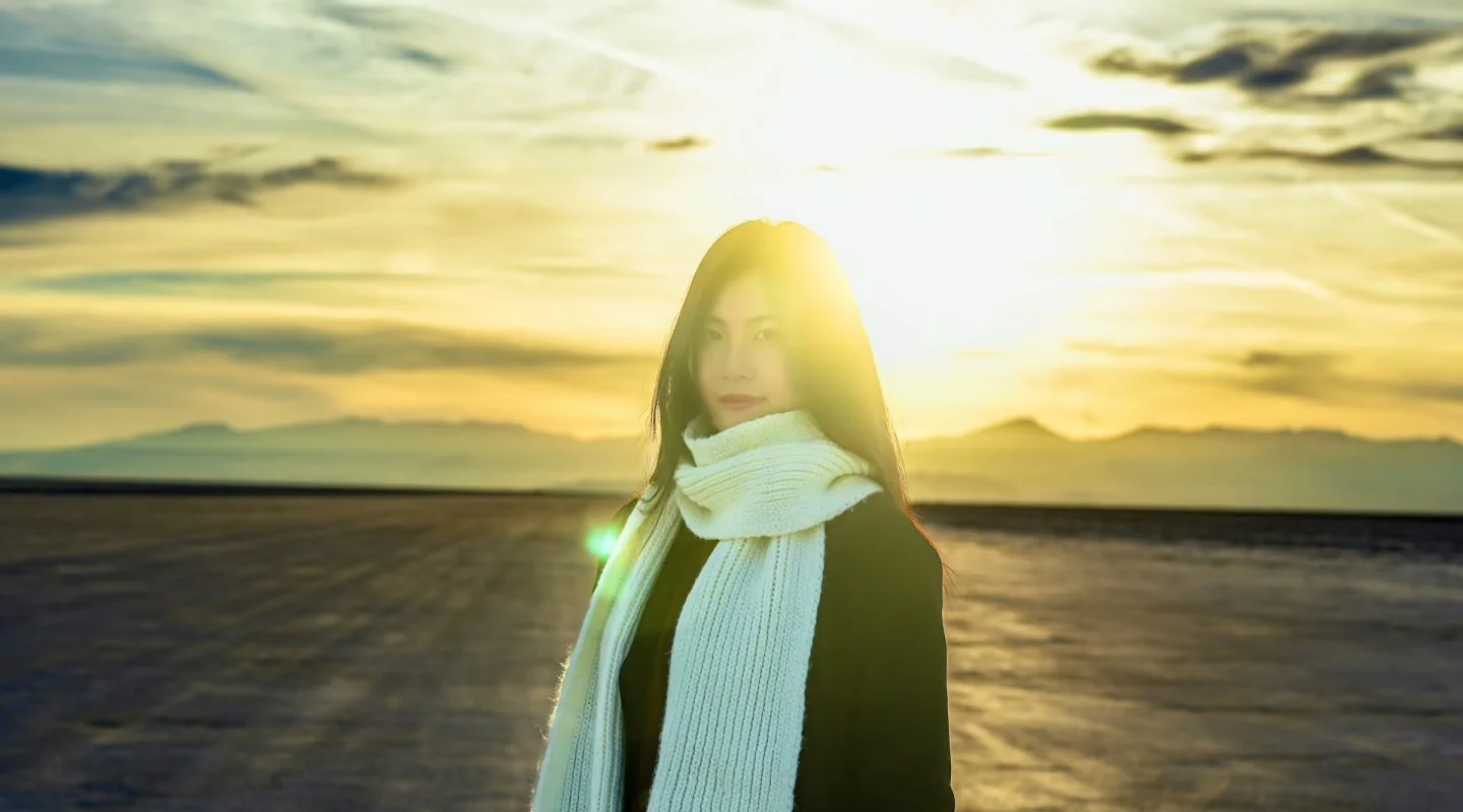 A woman silhouetted against a bright sunset on the salt flats