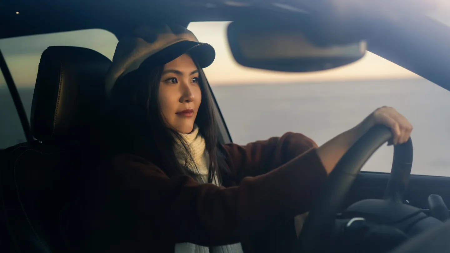 A woman seated behind the steering wheel at sunset