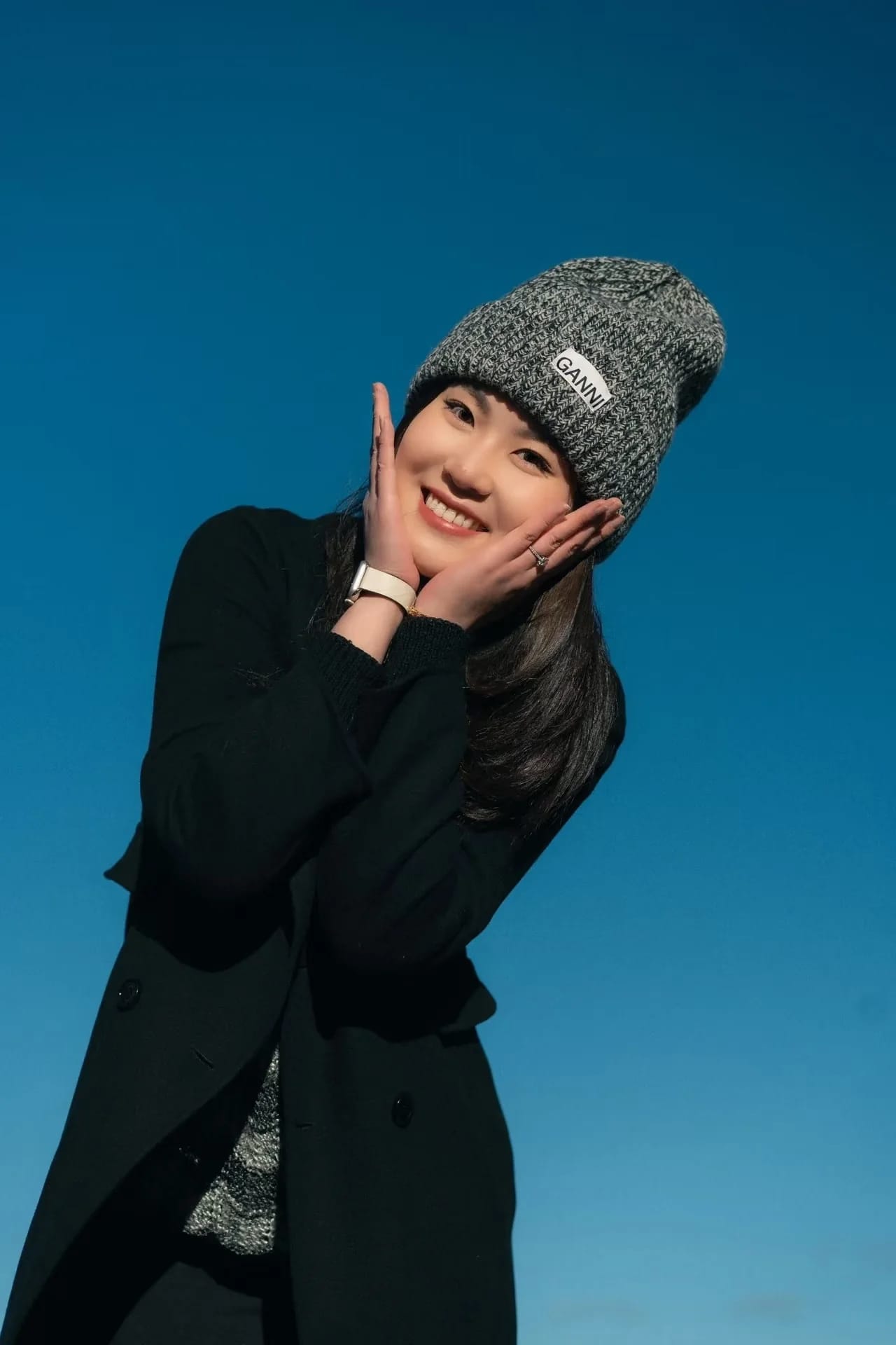 A woman resting her face in her hands beneath a clear blue sky