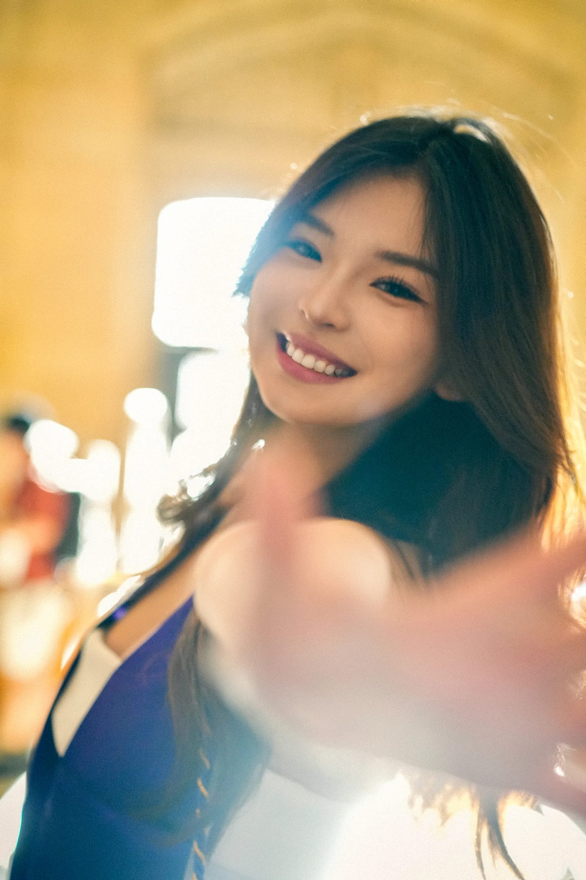 A graduate reaching toward the camera in warm window light